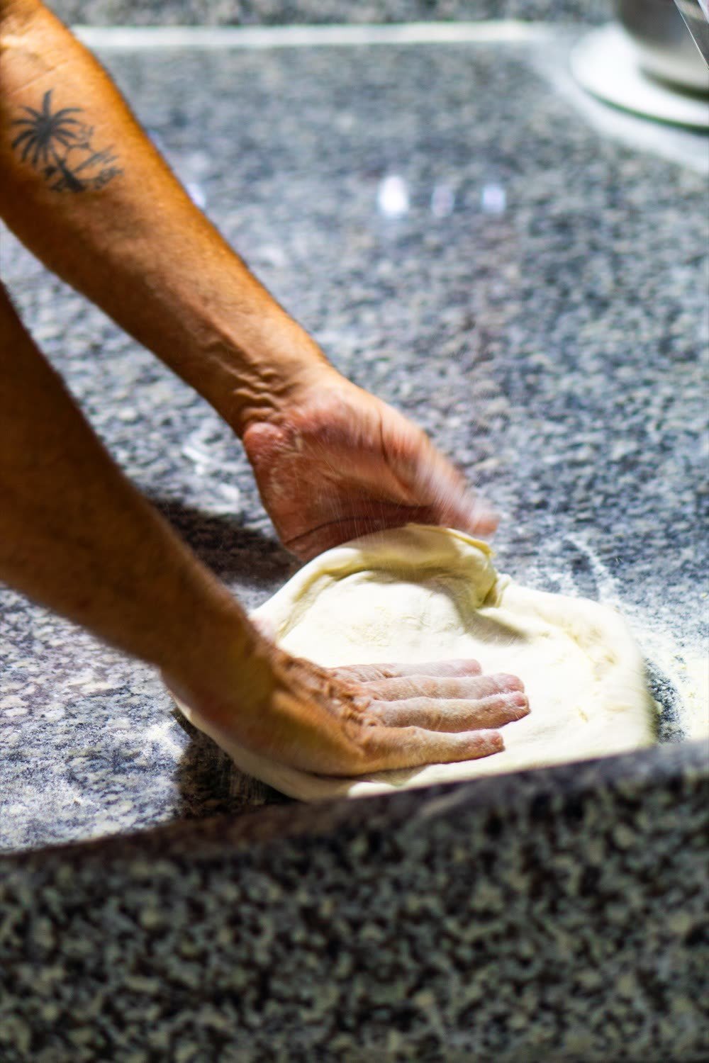 Mani che lavorano l'impasto della pizza napoletana