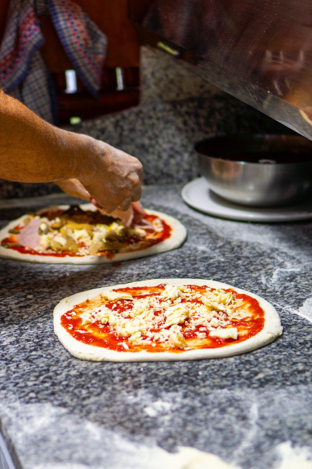 Luciano stende l'impasto della pizza sul banco